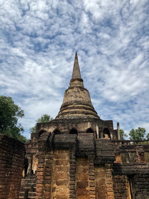 Free A historical temple with a towering spire set against a vibrant blue sky and white clouds. Stock Photo