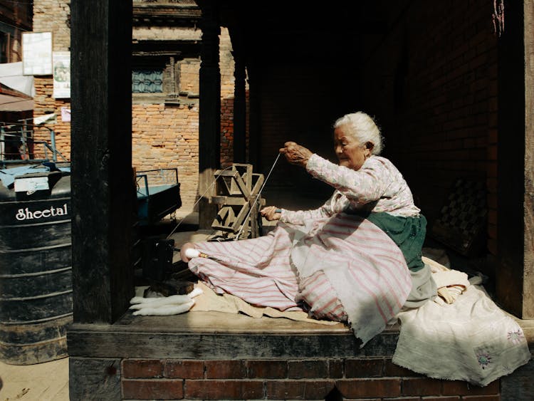 Senior Woman Weaving On A Terrace