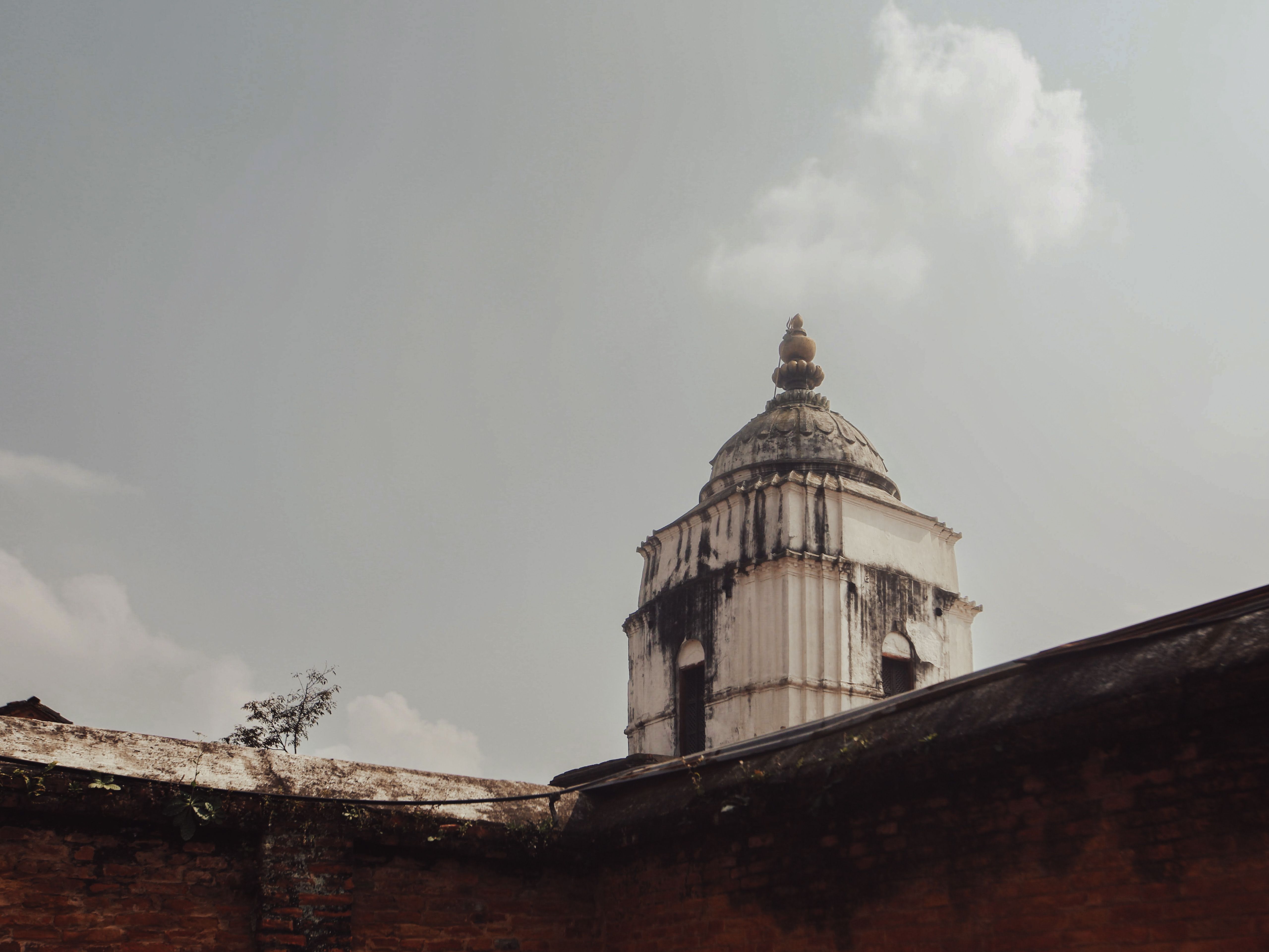 A historic architectural tower seen from a low angle under an overcast sky, showcasing its ancient design.