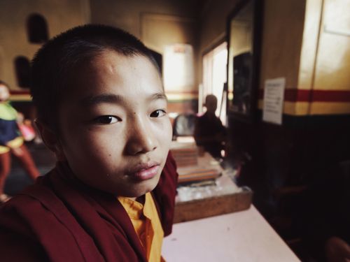 Free A contemplative young monk in traditional robes inside a dimly lit room. Stock Photo