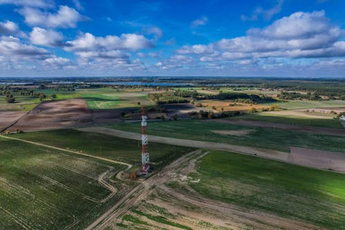 Red and White Metal Tower on Green Grass Field Under Blue Sky