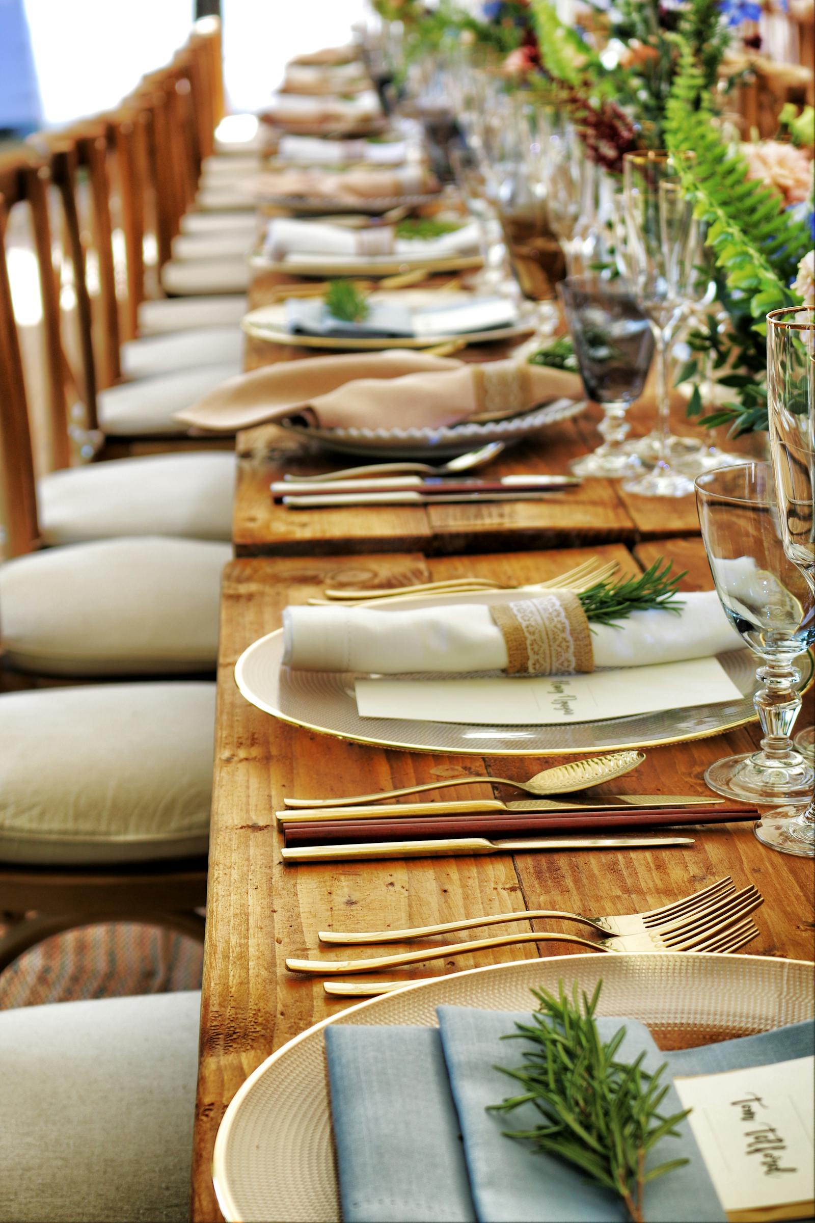 Elegant outdoor dining setup with rustic wooden tables, gold flatware, and neatly rolled napkins—reflecting the upscale, community-oriented atmosphere of Arbor Creek in Saskatoon.