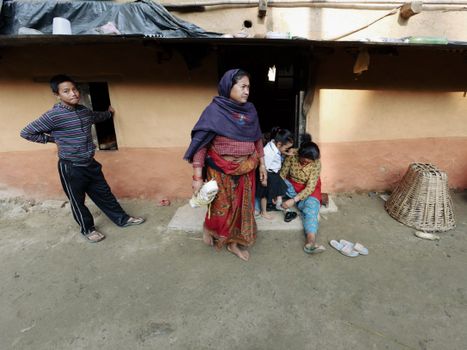 A family in traditional attire outside their rural home, showcasing everyday life.