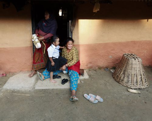 Free A mother and daughter sharing a moment on the doorstep, with a basket and footwear visible. Stock Photo