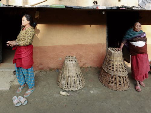 Women Standing Outside Concrete House Beside Woven Baskets