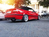 一辆充满活力的红色敞篷车停在绿树成荫的鹅卵石街道上