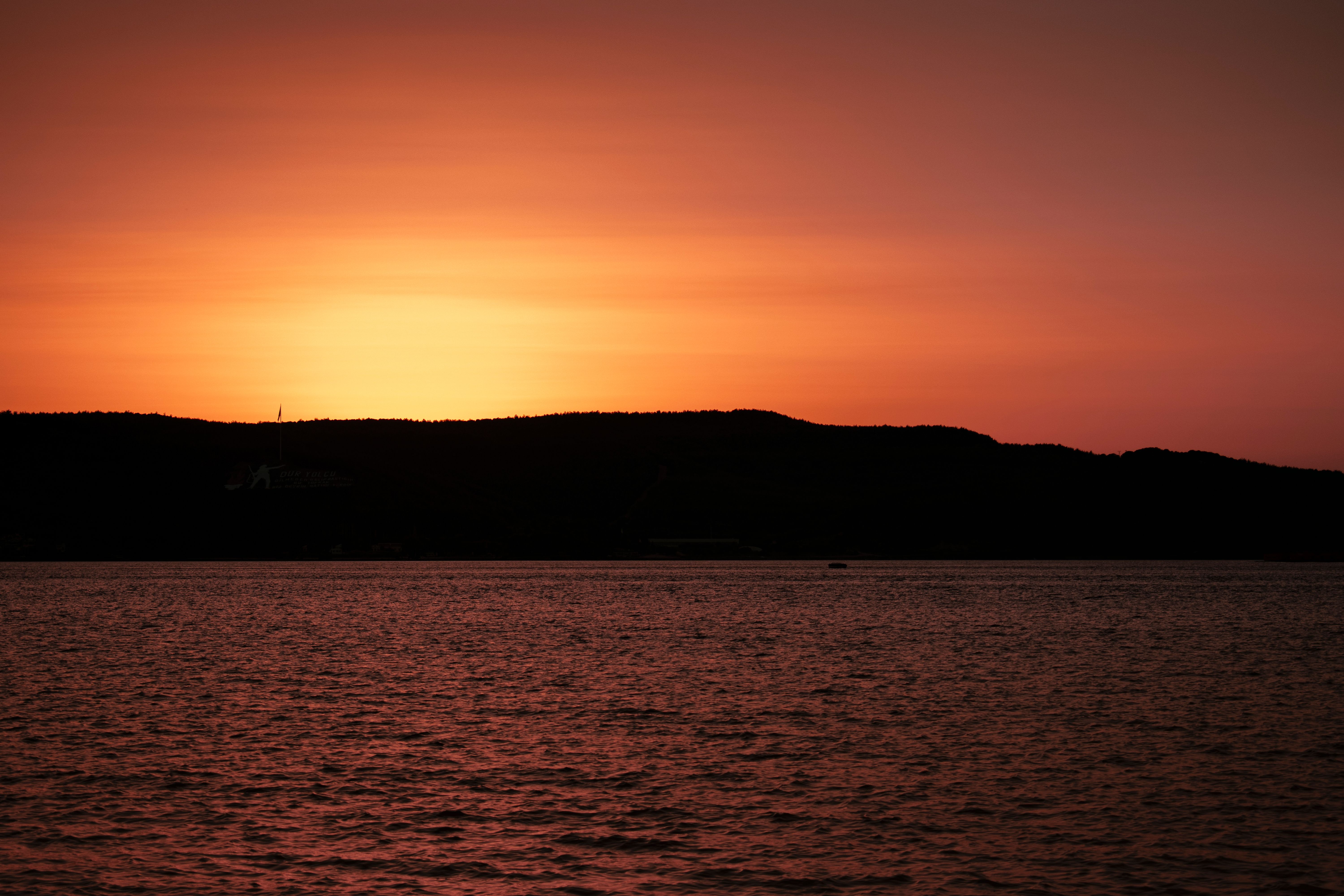 Silhouette of a Person Standing Near Body of Water During Sunset · Free ...