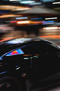 Blurred motion of a sleek black sports car speeding through urban Seoul at night.