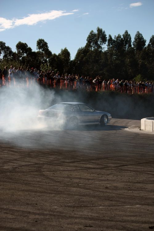 Free Dynamic drift car racing event with smoke and spectators on a sunny day. Stock Photo