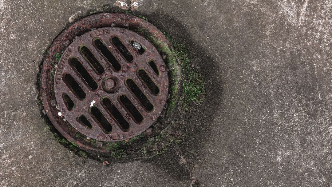 A rusted drain cover set into the ground