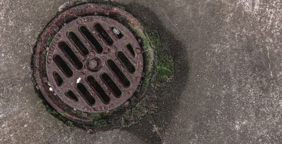 A drain grate at street level — shared drain runs are the main highway between stalls in a food court