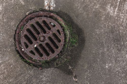 Free Close-up photo of a rusty drain grate with moss, offering a textured urban look. Stock Photo
