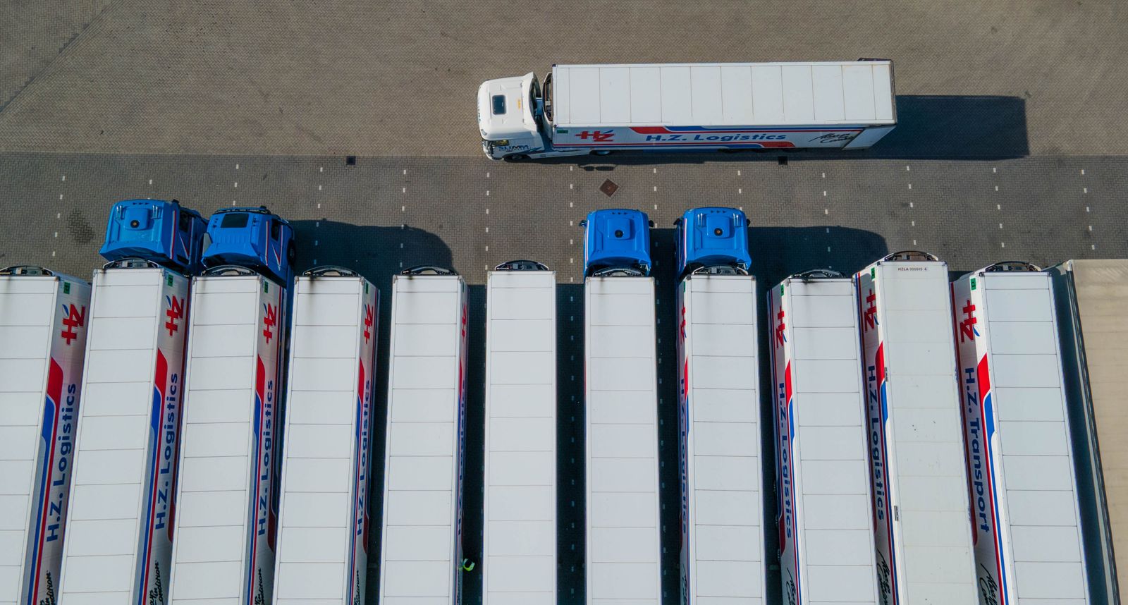 Top-down drone view of logistics trucks parked in an organized row