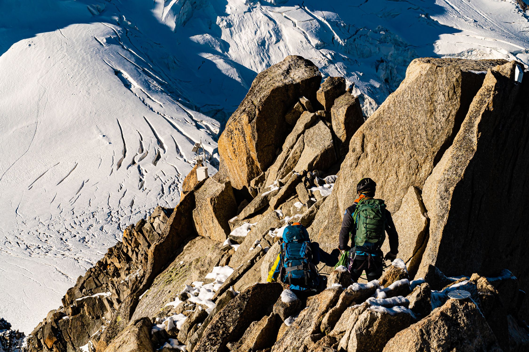 Climbers making their way up a rugged snowy mountain landscape in daylight Climbers making their way up a rugged snowy mountain landscape in daylight