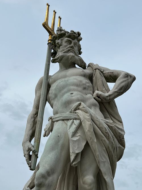 Free Beautiful marble statue of Neptune holding a trident, set against a cloudy sky, showcasing classical art. Stock Photo