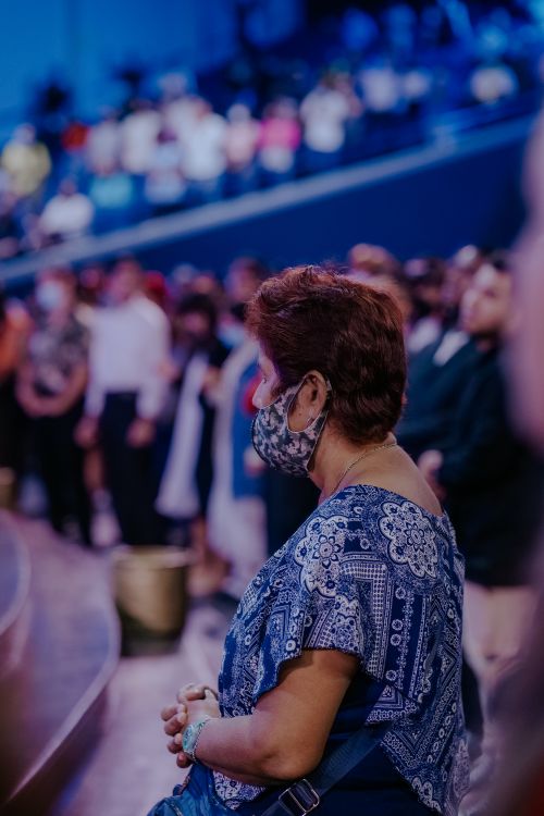 Free A woman in a face mask stands among a crowd during an indoor event. Stock Photo