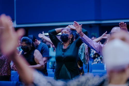 Praying People in Medical Masks Standing in a Church