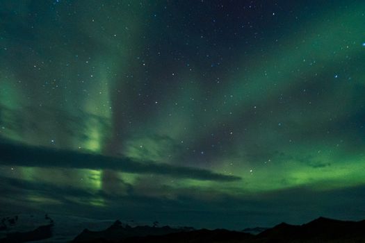 Breathtaking view of the aurora borealis illuminating the night sky over a mountain range, showcasing natural beauty.