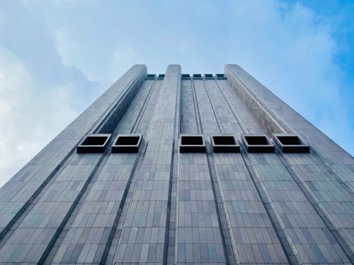 Free Low angle view of a towering skyscraper against a blue sky in New York City, showcasing modern architecture. Stock Photo