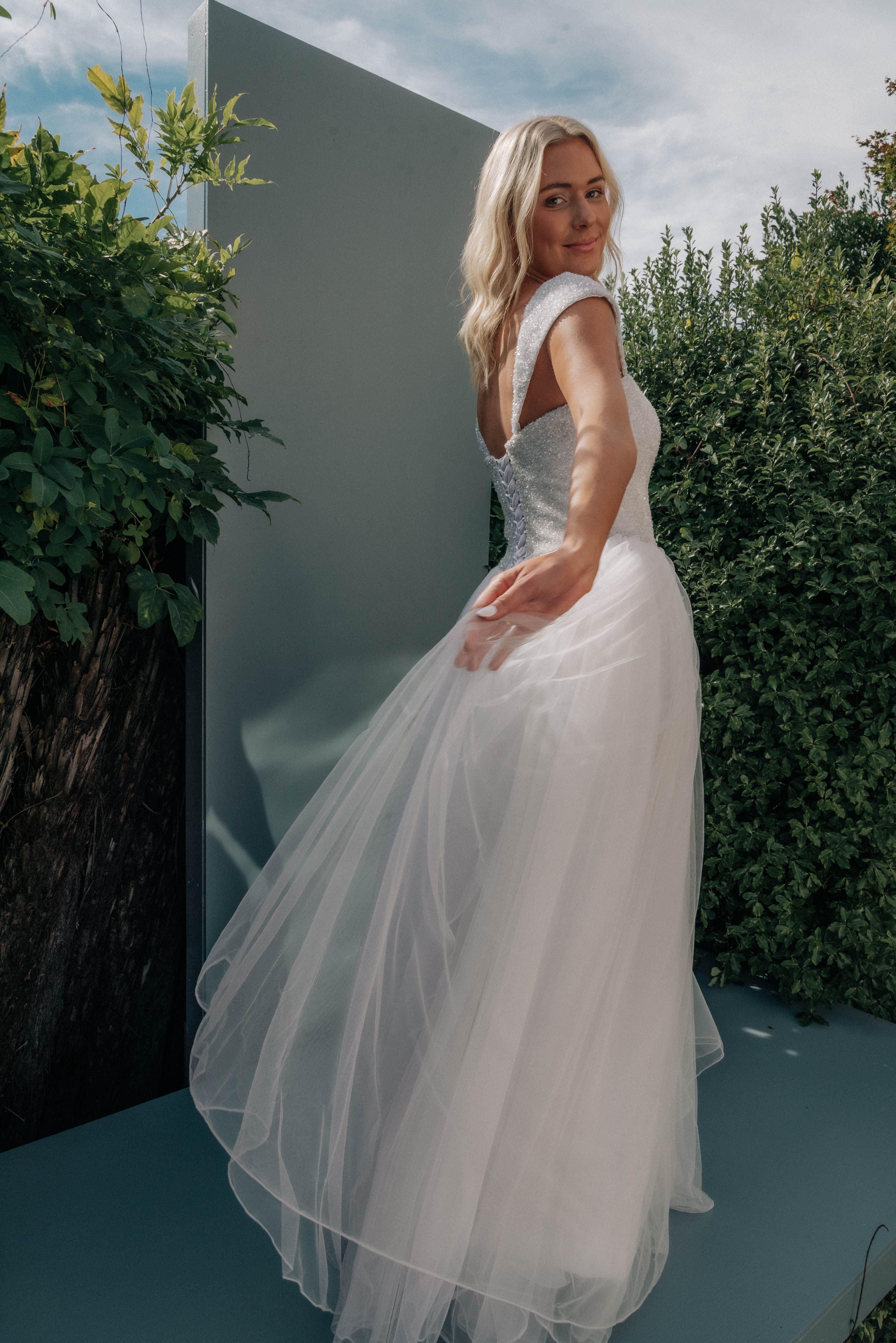 Beautiful bride in a flowing white dress, captured in an outdoor garden scene.