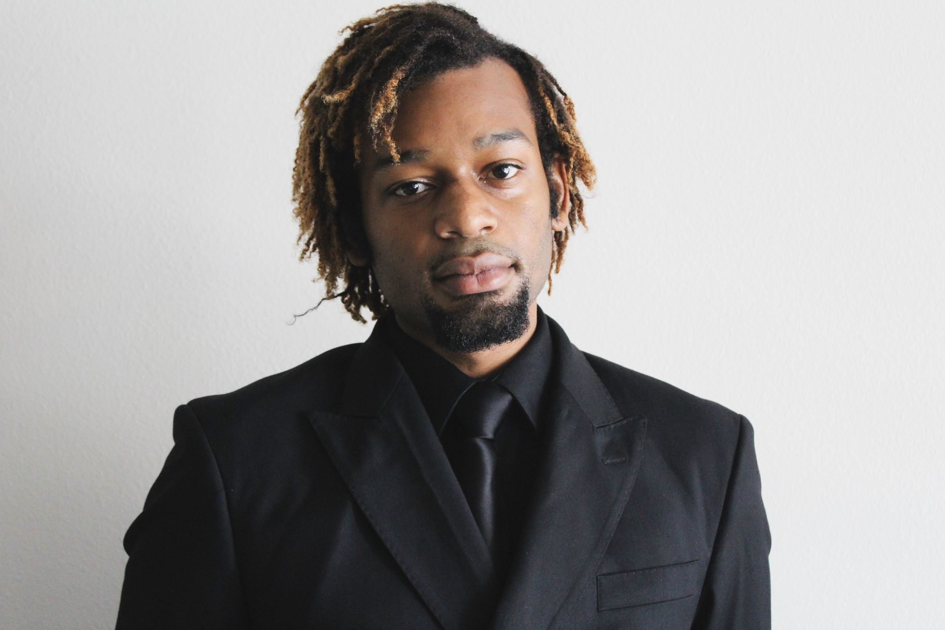 Sophisticated man in a black suit against a plain background for corporate or fashion use.