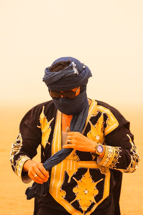 Person with Headscarf and Sunglasses Standing on Sahara Desert