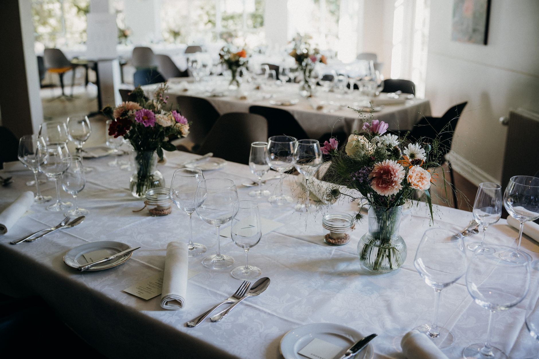 Beautifully arranged wedding reception with intricate floral table settings and elegant glassware.