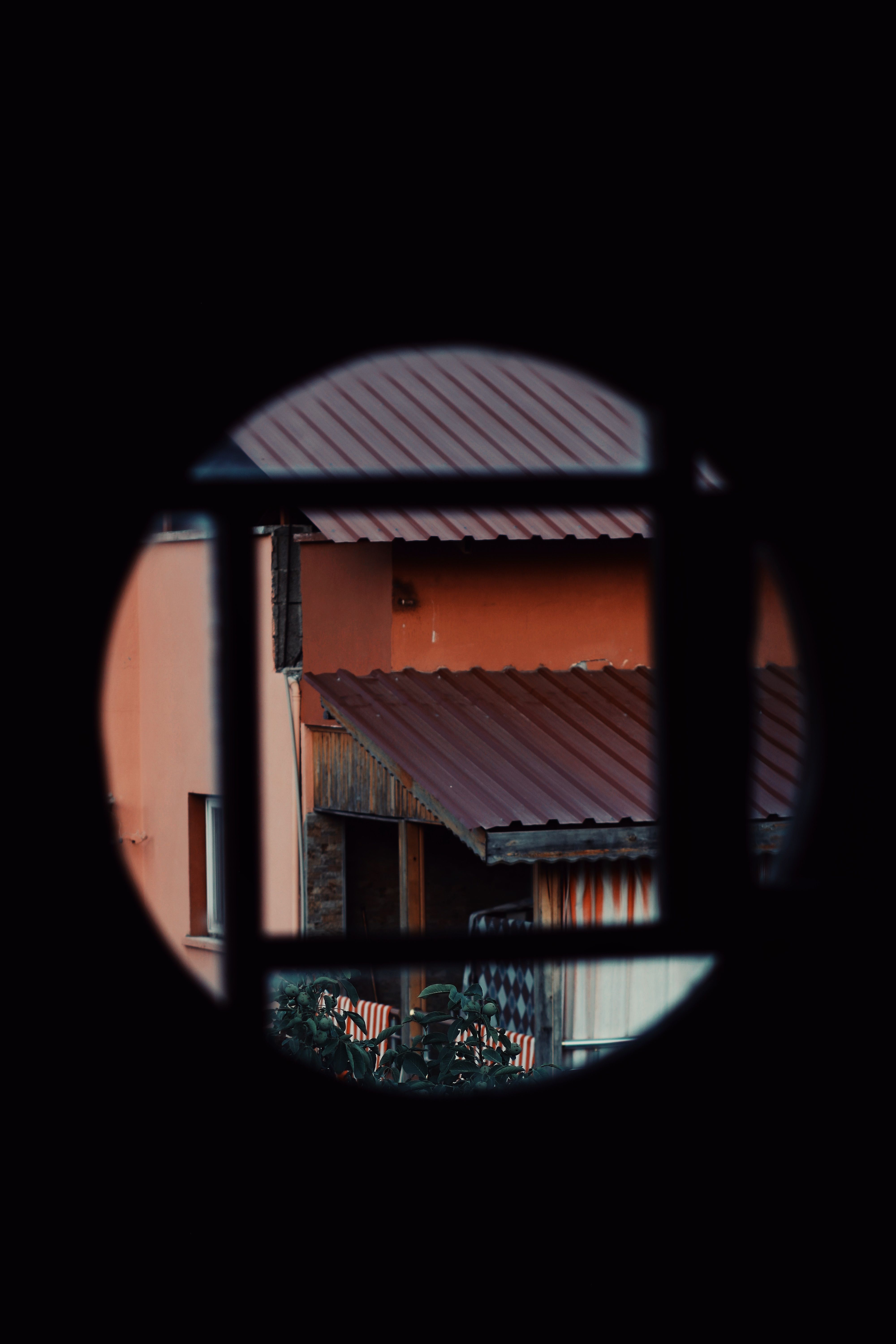 A silhouette view of residential structures through a round aperture, emphasizing architectural designs.