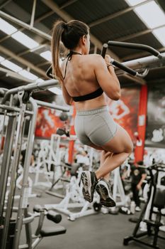 Strong woman doing pull-ups at a gym showcasing fitness and strength.