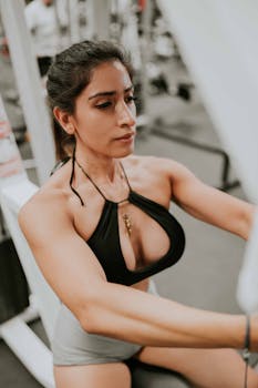 A woman intensely focusing during a workout session in a modern gym setting.