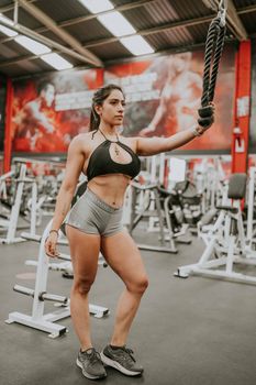Fitness woman exercising at the gym using a training rope, focusing on strength and endurance.
