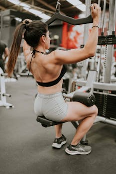 Fit woman with long hair using gym equipment to focus on back muscles and fitness.