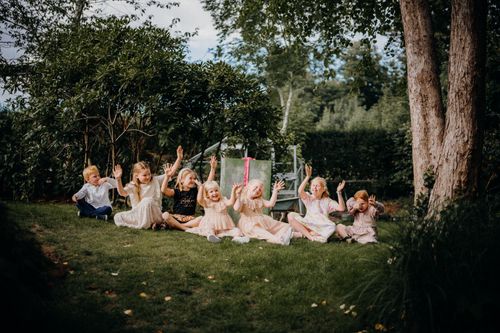 Free A group of happy children playing outdoors on a sunny day, enjoying togetherness in a lush green backyard. Stock Photo