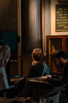 Students engrossed in study within a vintage-style, dimly lit classroom setting.