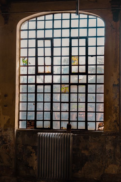 Free A historic window with grill pattern and old radiator in an abandoned building interior. Stock Photo