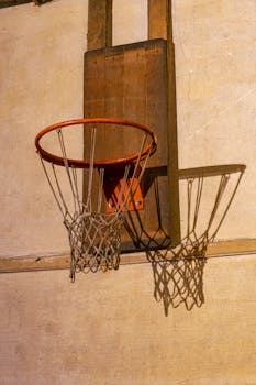 Close-up of a basketball hoop casting a shadow on a wooden wall, indoors.
