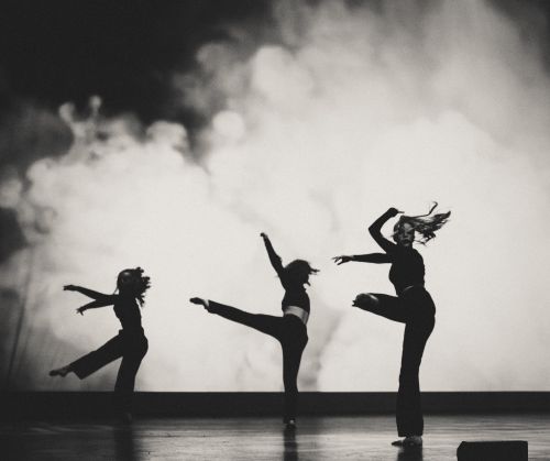 Free Three dancers perform energetically on stage against a backdrop of smoke, showcasing dynamic choreography. Stock Photo