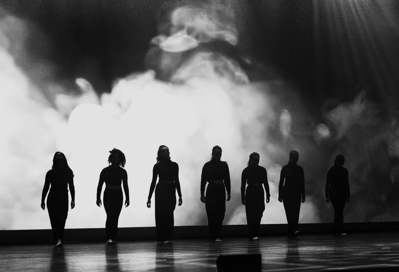 Performers silhouetted against a lit stage backdrop — photo by Ricardo Oliveira on Pexels