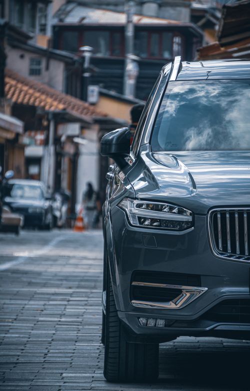 Free Stylish Volvo SUV parked in a quaint cobblestone street, showcasing modern automotive design. Stock Photo