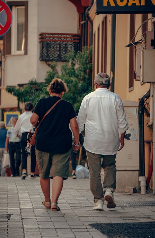 Free A couple of adults walking on a city sidewalk, holding hands in a casual urban environment. Stock Photo