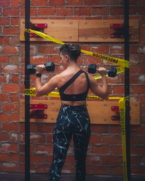 Free Athletic woman working out with dumbbells in an industrial-style gym environment. Stock Photo