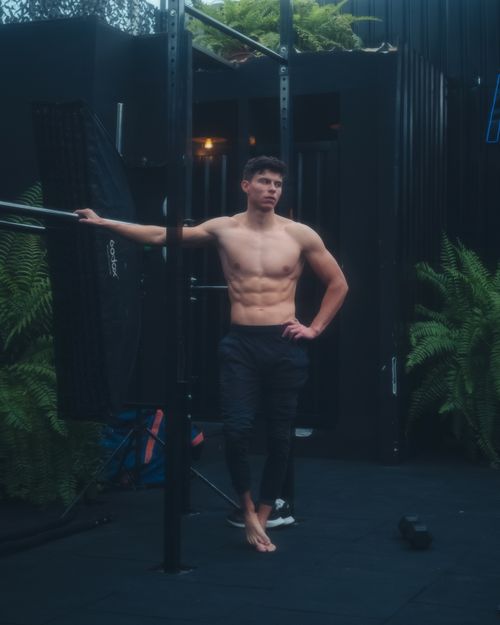 Free Muscular man posing topless outdoors with metal gym equipment, showcasing toned physique. Stock Photo