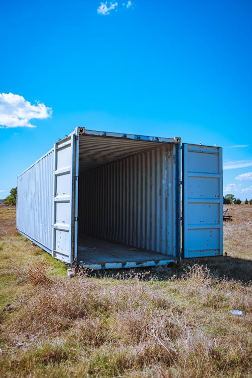 A Shipping Container on Grass Under the Blue Sky