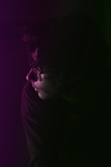 Artistic side profile portrait of a woman with colorful lighting and mysterious ambiance.