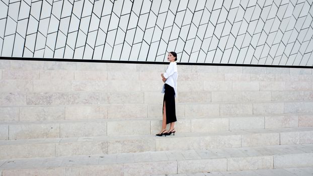 Stylish woman standing on a geometric staircase in a modern setting, showcasing elegance and sophistication.