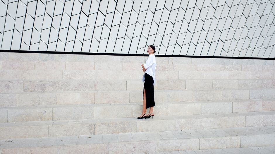 Stylish woman standing on a geometric staircase in a modern setting, showcasing elegance and sophistication.