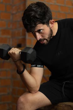 A man intensely focused while lifting a dumbbell indoors. Perfect for fitness themes.