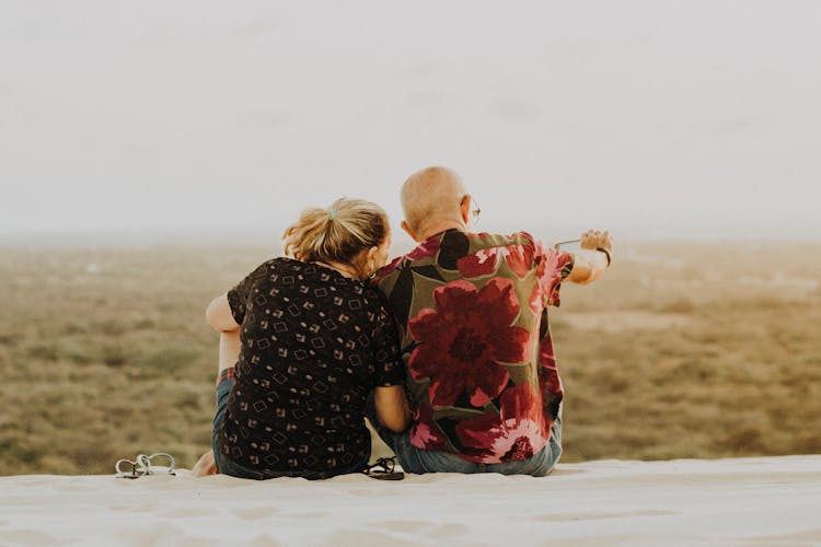 Two People Sitting On Sand