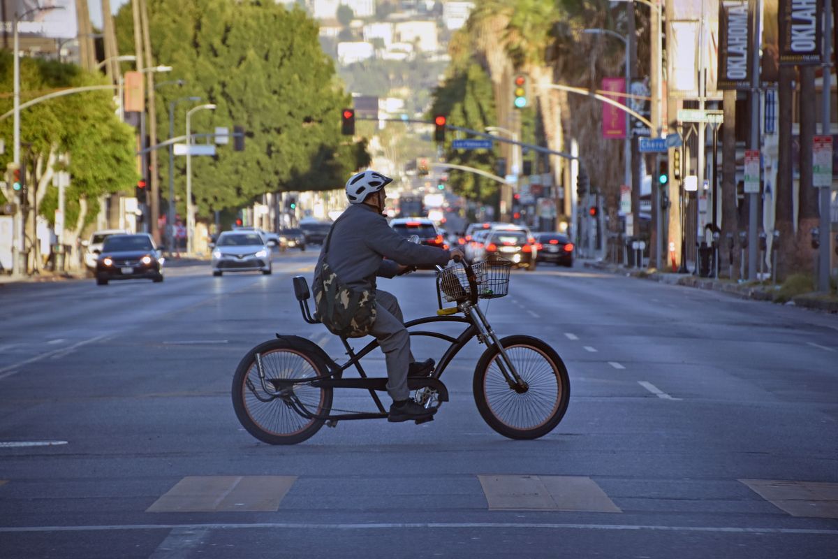 Helmeted cyclist riding along a busy city street