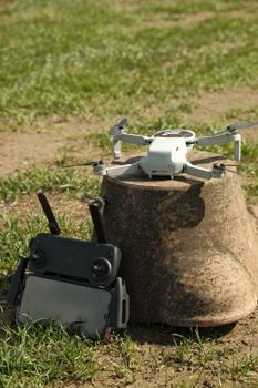 Drone and remote resting on a ceramic pot in a grassy field.
